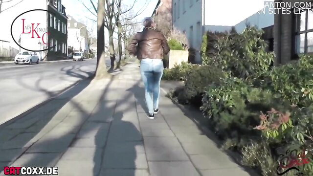 Blonde woman in tight jeans and leather jacket walking on street
