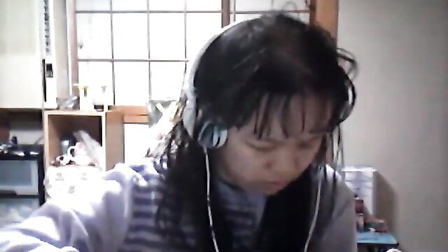 Asian schoolgirl with headphones in kitchen, long black hair