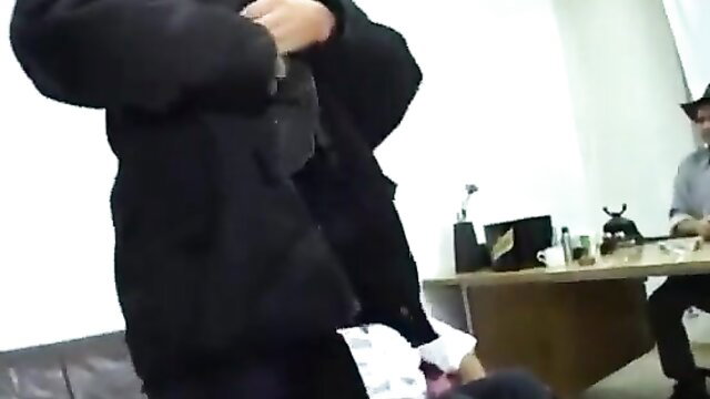 Mature piss whore Kim in puffy jacket holds cock over desk