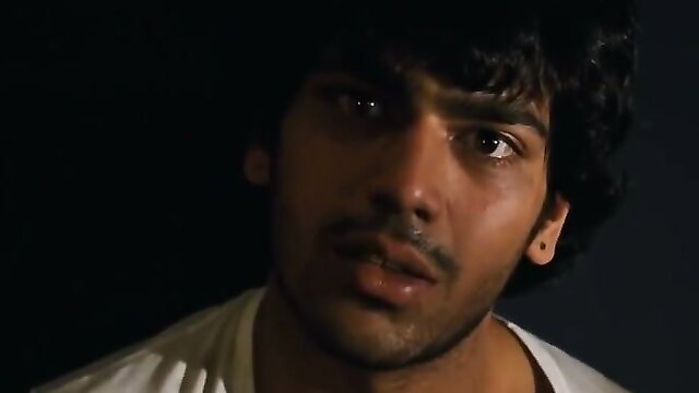 Handsome Indian man with curly hair and mustache in dim-lit closeup