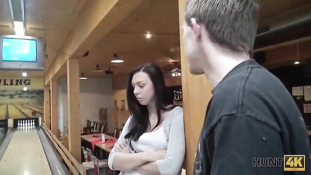 Brunette in white top arms crossed talks to guy at bowling alley in HUNT4K pickup
