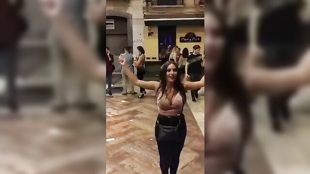 Busty brunette in low-cut top arms outstretched skipping rope outdoors