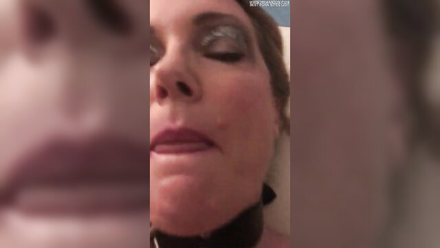 Closeup of mature woman's glossy lips and eyes in collar, deepthroat tease