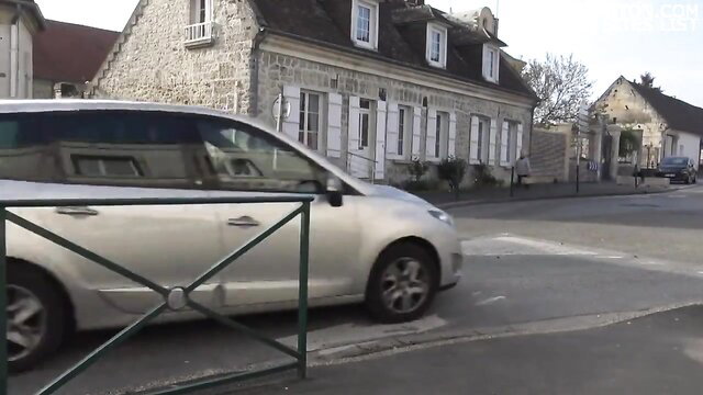 Silver car parked on French village street, stone houses background