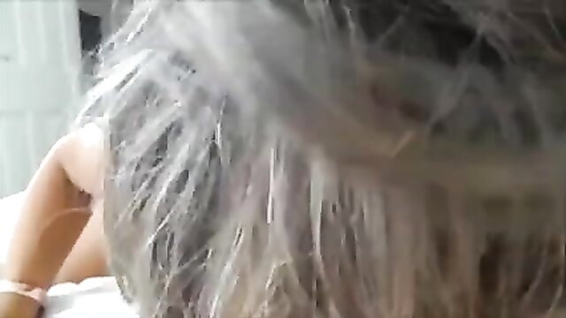 61-year-old mature woman with gray hair lying nude on bed, sexy pose