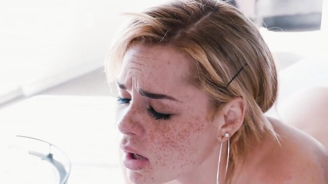 Blonde woman with freckles grimacing in close-up facial cumshot reaction