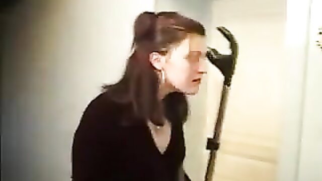 Brunette French MILF in black top sniffs vacuum cleaner handle close-up