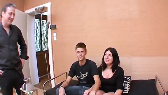 Nervous brunette with young guy on bed, older man watches closely