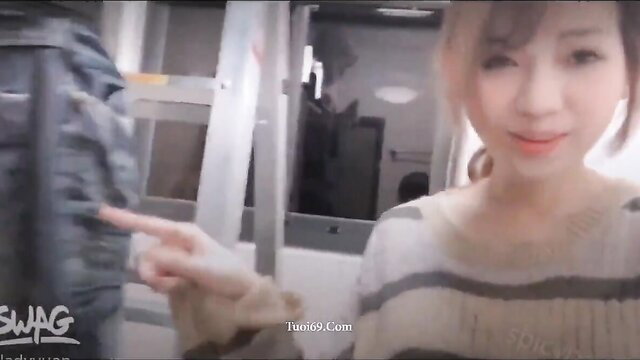 Cute Asian chinagirl in sweater points playfully, smiling closeup