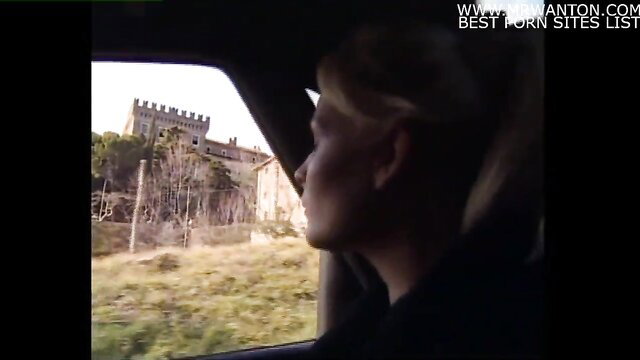 Blonde woman in car gazes at castle, sex slave allure