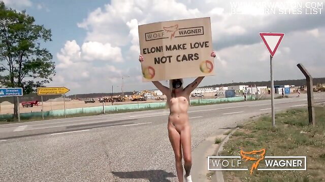 Kitty Blair nude Tesla protest for Elon Musk, holding sign 'Eloni make love not cars'