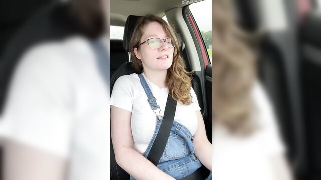 Nerdy country girl in glasses and overalls smiles in car seat
