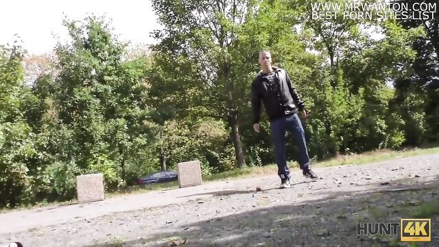 Man in leather jacket stands by car in woods, Hunt4K outdoor tease