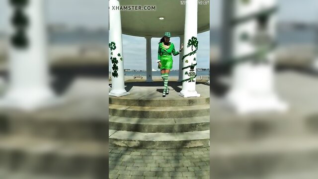 Hot babe in skimpy green St. Patrick's Day dress and stockings on outdoor steps