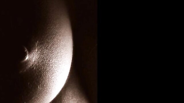 Closeup of woman's large bare breast and erect nipple in arousing retro monochrome