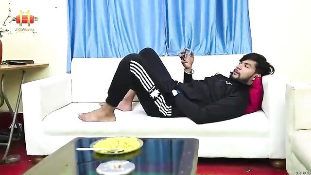 Indian man relaxing on couch in Adidas tracksuit, phone in hand