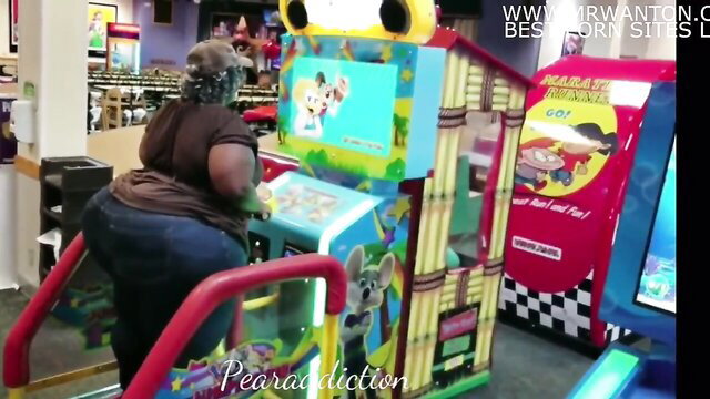 Big black ass woman in tight jeans on arcade ride machine