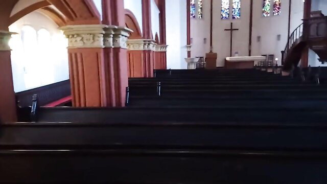 Empty church interior with red arches, pews and stained glass windows