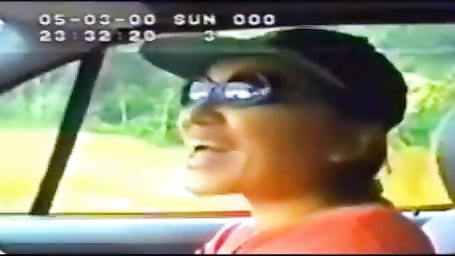Malay woman Kak Wan smiling in car, orange shirt, shades, amateur style