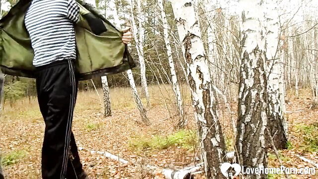 Guy in tracksuit holds jacket open for stepmom on forest walk