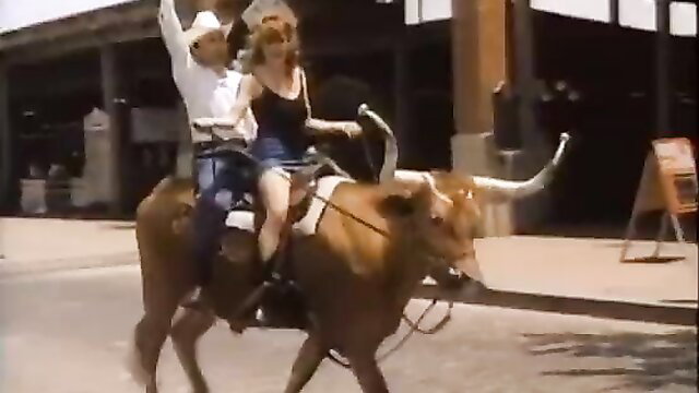 Cowboy and redhead woman riding bull in Singapore Sling 1999 movie scene