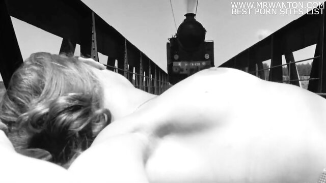 Blonde woman nude ass up on bridge with train approaching