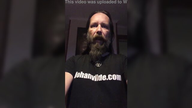 Bearded long-haired man in black t-shirt with johansvilde.com logo verification video
