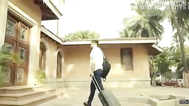 Indian man in white shirt and pants pulling suitcase outside house