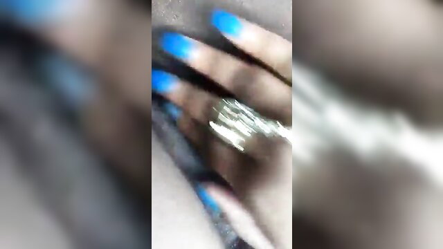 Closeup of black woman's blue nailed hand showing off large silver ring
