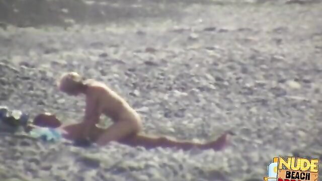 Blonde woman nude on beach, man kneeling behind in outdoor sex