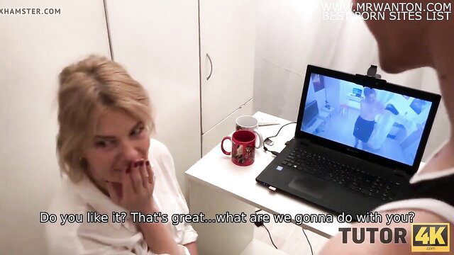 Blonde literature tutor in white top at desk with laptop, seductive gaze