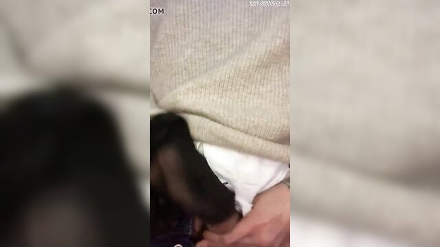 Woman in gray sweater and white panties holds black dildo near crotch