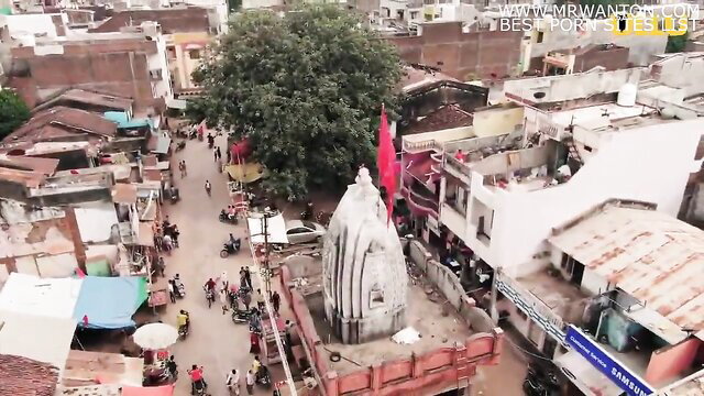 Aerial view of Indian temple with red flags in crowded village street