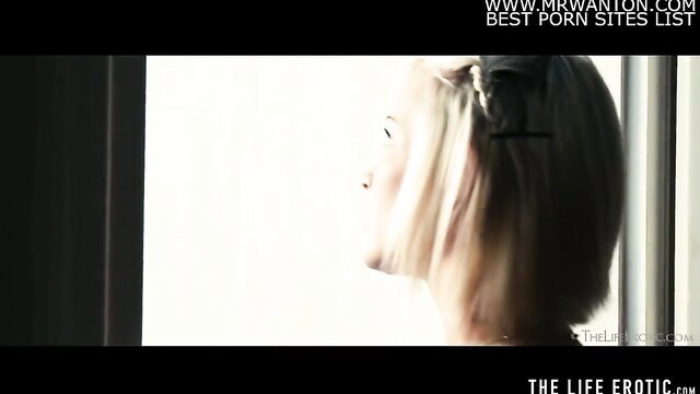 Cute blonde looks out window, seductive profile pose