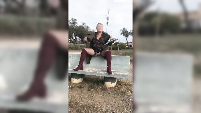 Bourgeoise MILF exhibits in leather coat, thong, thigh-high boots on bench