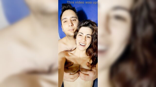 Topless Italian couple selfie, smiling man hugs busty brunette girlfriend