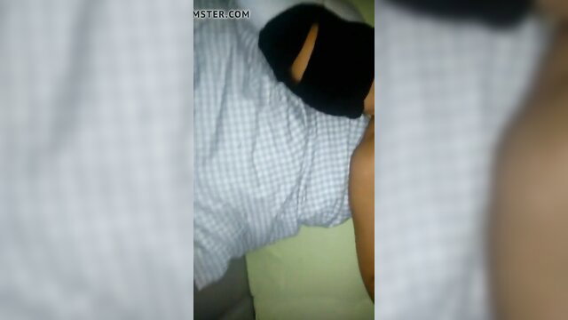 Asian girl in balaclava mask lying in bed, mouth open for cumshot
