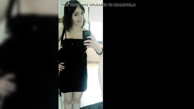 Smiling amateur brunette in tight black mini dress takes mirror selfie