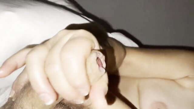 Amateur handjob closeup of woman's hand stroking hard cock on bed