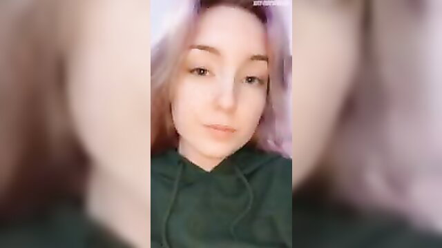 Cute pink-haired girl with almond eyes in green hoodie, closeup face