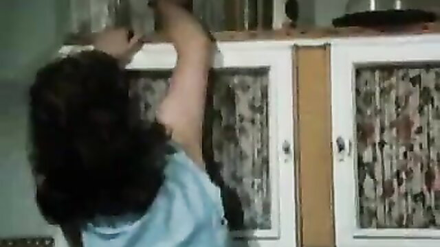 Brunette reaching up in kitchen, classic adult tease