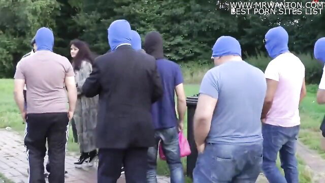 Group of masked men surround fat German whore in park outdoors