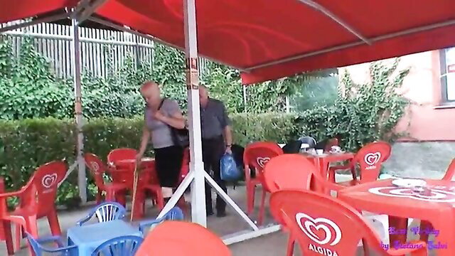 Elderly couple at outdoor ice cream stand, young girl nearby
