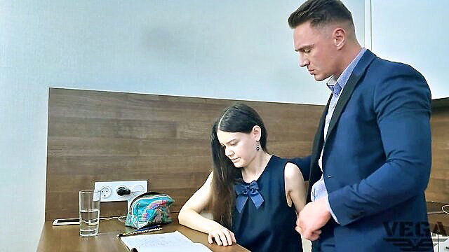 Teen stepsister in blue dress leans over helping bro at desk
