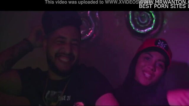 Smiling Arab couple in hijab and hats posing intimately at neon party