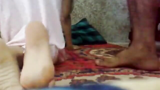 Indian uncle bare feet closeup on rug with auntie in salwar kameez