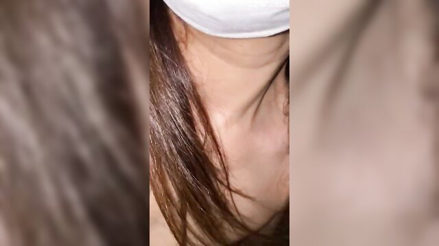 Blurry closeup of woman's neck, long brown hair, white mask in JAV nude walk