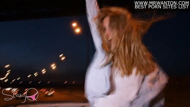 Redhead babe in white top dances erotically at night under lights