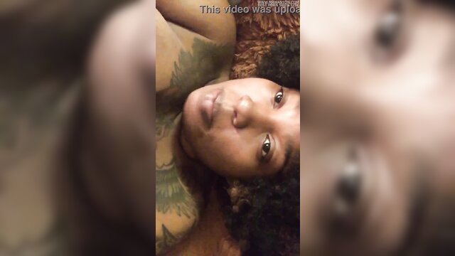 Closeup of busty black Hazelnutxxx with tattoos smiling at camera