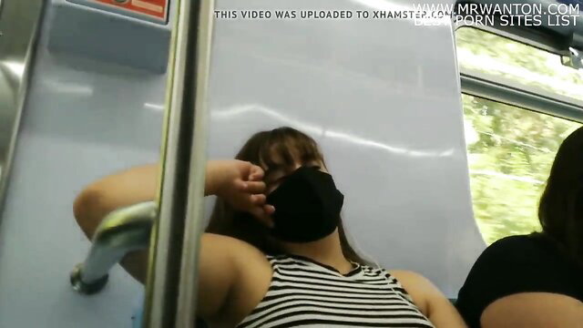 Asian babe in striped tank top leans arm on subway pole, upskirt tease